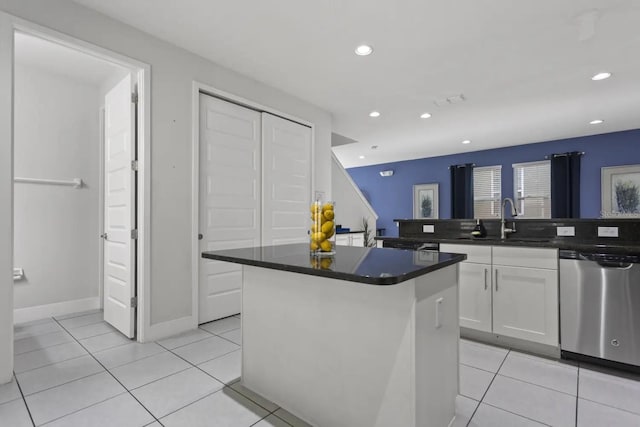 kitchen with a kitchen island, white cabinetry, sink, light tile floors, and stainless steel dishwasher