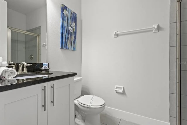 bathroom with a shower with shower door, vanity, toilet, and tile flooring