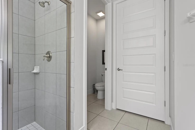 bathroom featuring tile flooring, an enclosed shower, and toilet