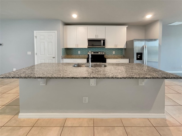 kitchen with appliances with stainless steel finishes, a kitchen breakfast bar, and an island with sink