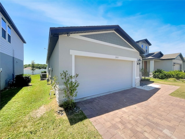 view of side of home featuring a lawn, a garage, and central air condition unit