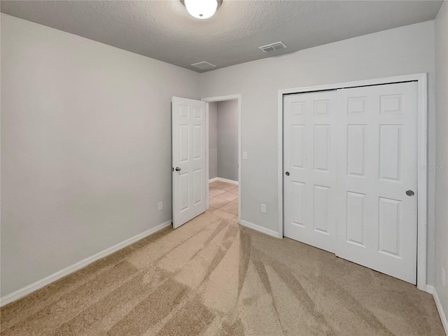 unfurnished bedroom featuring light colored carpet, a closet, and a textured ceiling