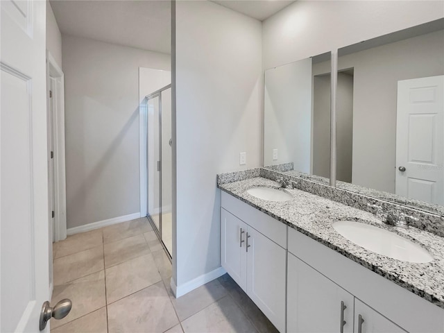 bathroom featuring tile flooring, dual sinks, oversized vanity, and an enclosed shower