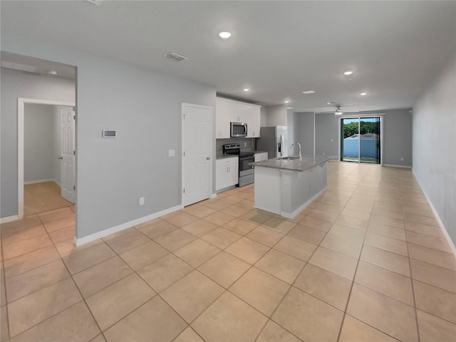 kitchen featuring white cabinetry, appliances with stainless steel finishes, an island with sink, light stone counters, and sink