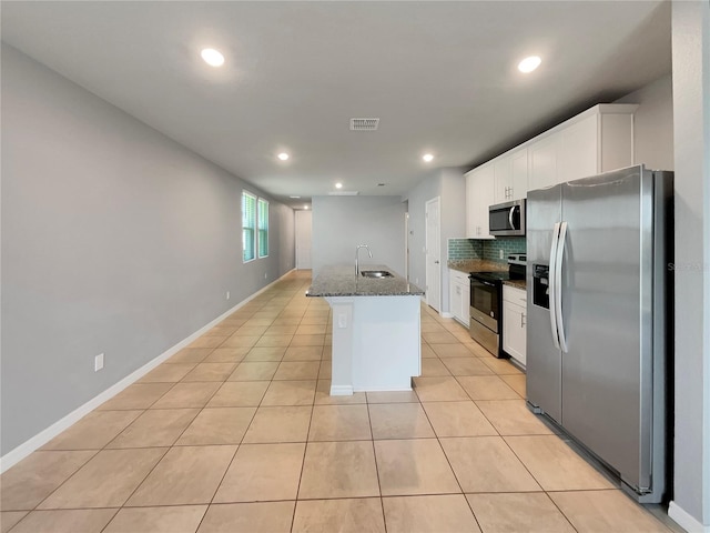 kitchen with white cabinets, backsplash, stainless steel appliances, light tile floors, and dark stone counters