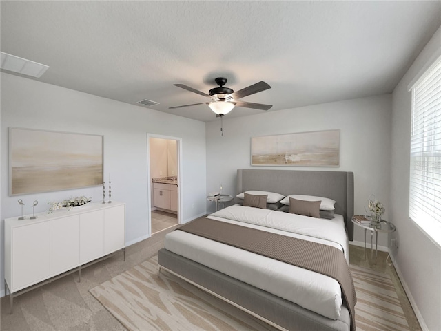 bedroom with light carpet, ceiling fan, and ensuite bathroom