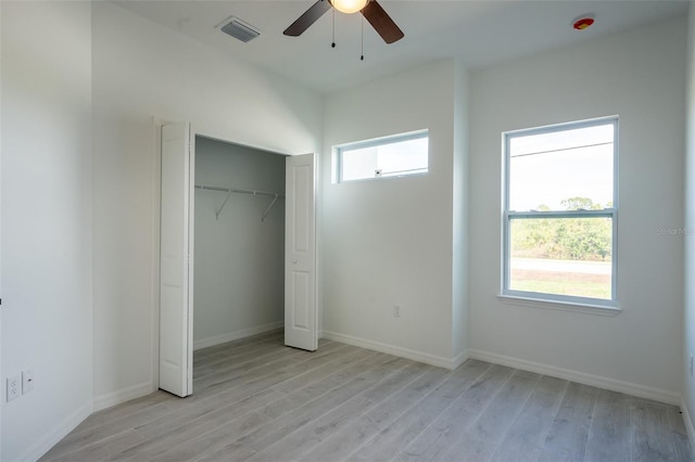 unfurnished bedroom featuring ceiling fan, a closet, light wood-type flooring, and multiple windows