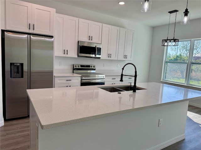 kitchen featuring sink, light stone counters, a kitchen island with sink, white cabinets, and appliances with stainless steel finishes