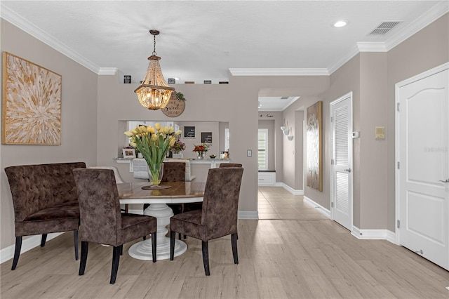 dining room with a chandelier, ornamental molding, and light wood-type flooring