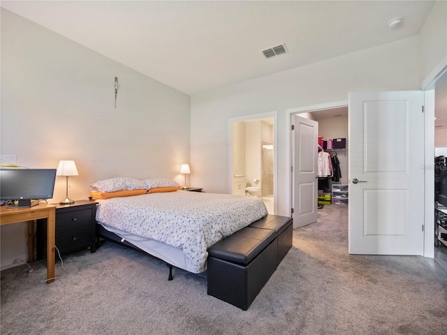 carpeted bedroom with ensuite bath, a walk in closet, and a closet