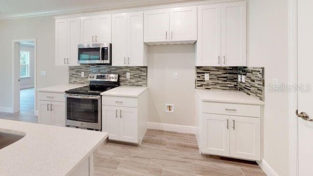 kitchen featuring crown molding, tasteful backsplash, stainless steel appliances, light hardwood / wood-style floors, and white cabinets