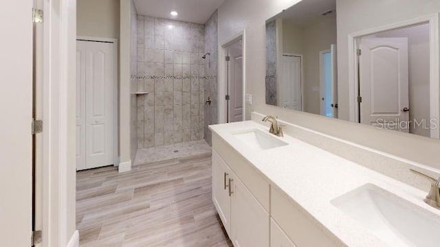 bathroom with a tile shower, vanity, and hardwood / wood-style flooring