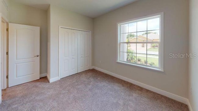 unfurnished bedroom with a closet and light carpet