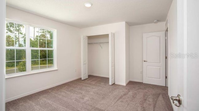 unfurnished bedroom featuring a closet and light carpet