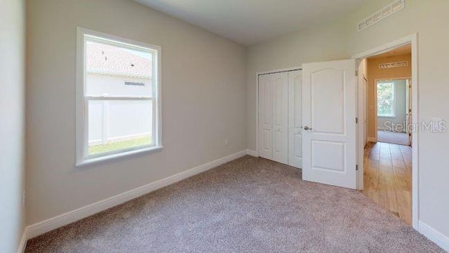 unfurnished bedroom with light carpet and a closet