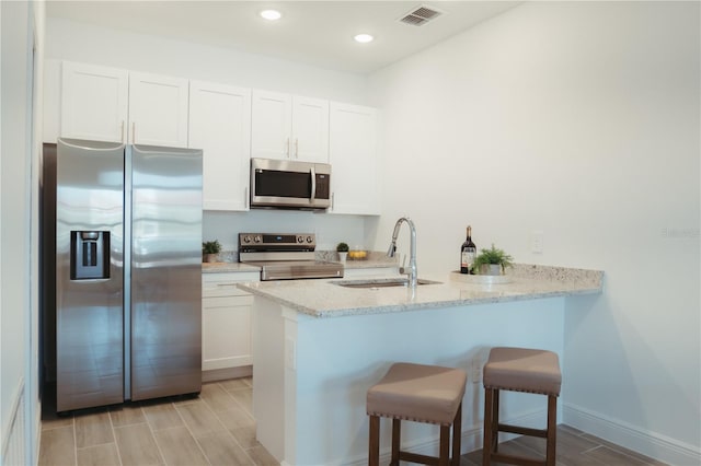 kitchen with light hardwood / wood-style flooring, stainless steel appliances, white cabinetry, and sink