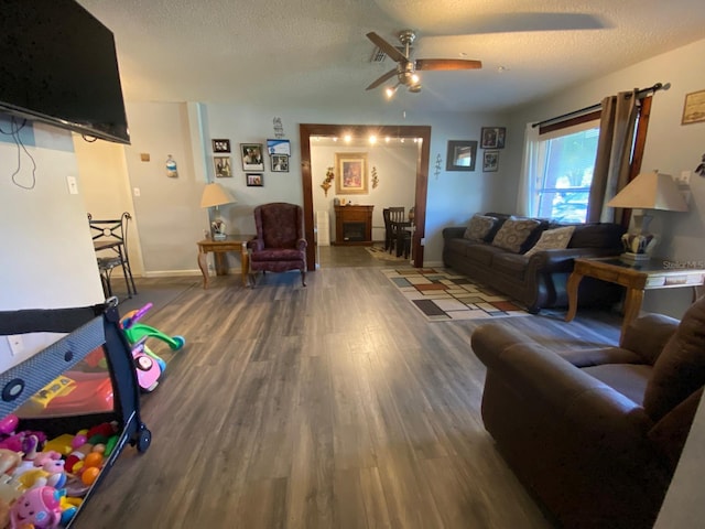 living room with ceiling fan, dark wood-type flooring, and a textured ceiling