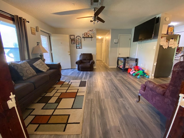 living room featuring wood-type flooring, ceiling fan, and a textured ceiling