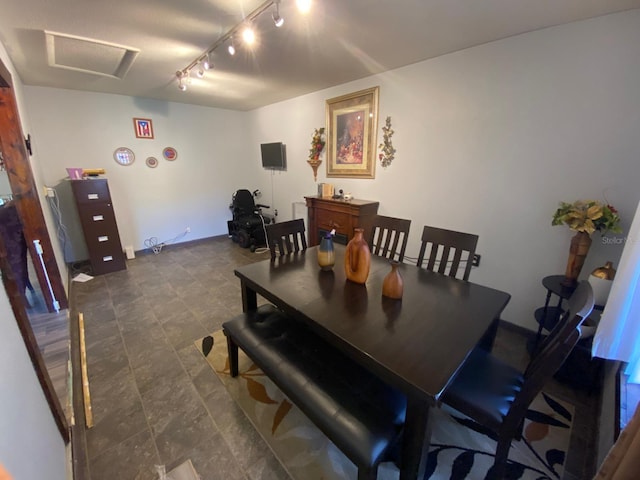 dining room featuring rail lighting and dark tile floors