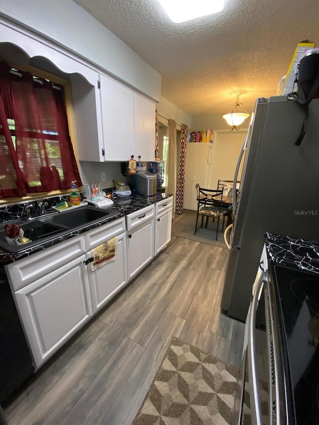 kitchen with stove, white cabinetry, hardwood / wood-style floors, sink, and a textured ceiling