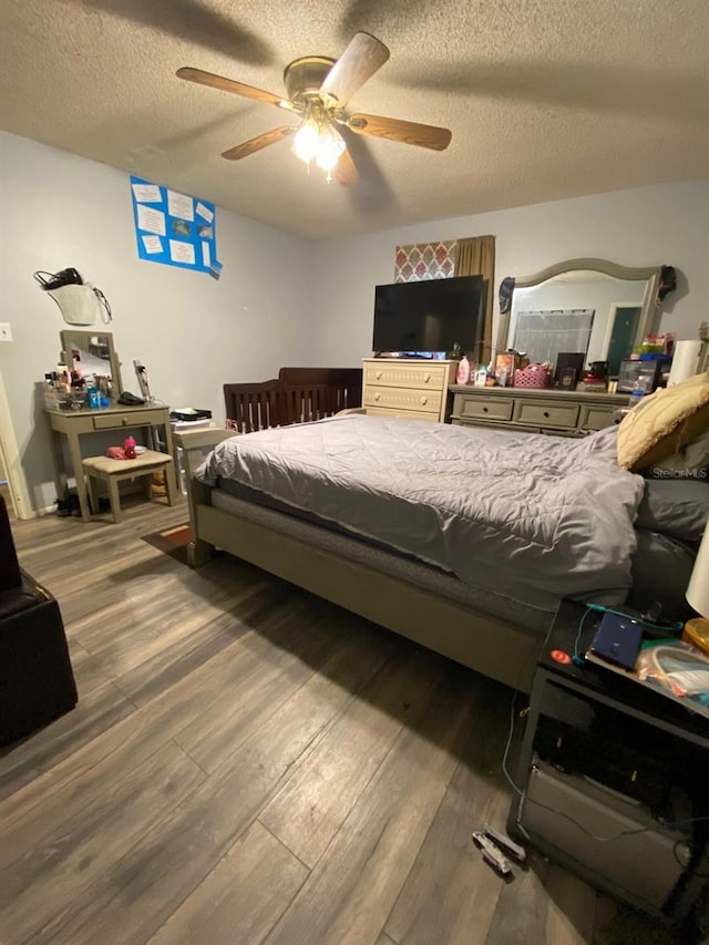 bedroom featuring ceiling fan, dark hardwood / wood-style floors, and a textured ceiling