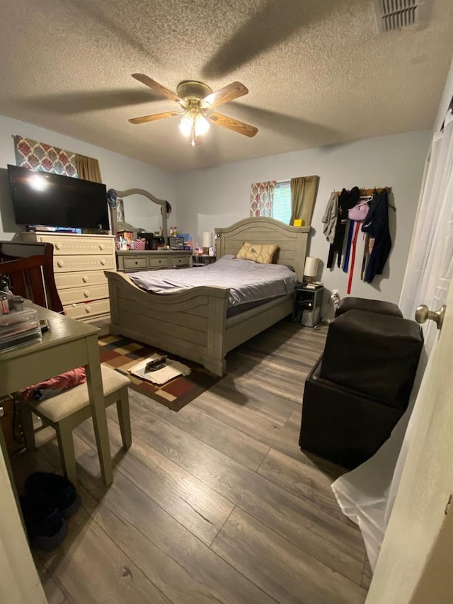 bedroom with dark hardwood / wood-style floors, ceiling fan, and a textured ceiling