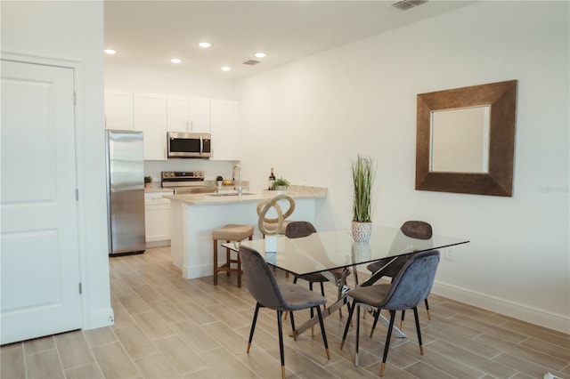 dining space with light hardwood / wood-style flooring and sink