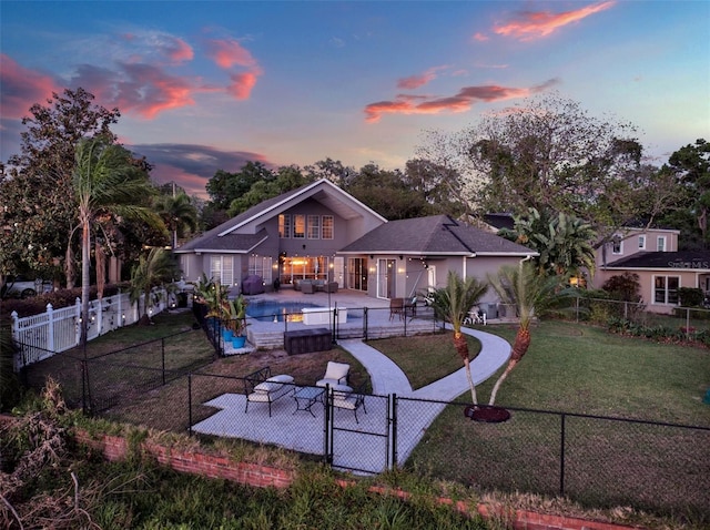 back house at dusk featuring a fenced in pool, a lawn, and a patio