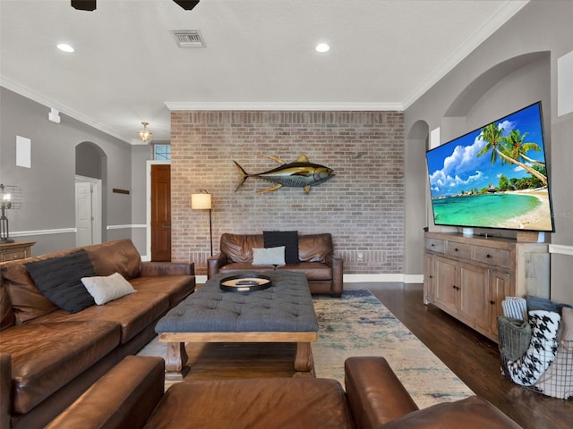 living room featuring dark hardwood / wood-style floors, ornamental molding, and brick wall