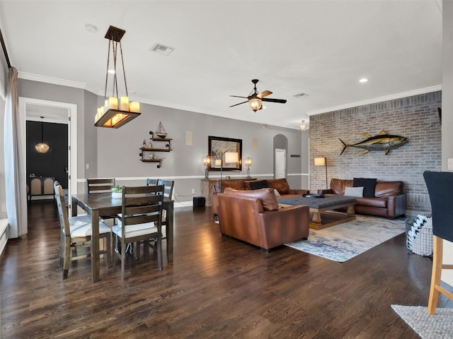 living room with ceiling fan, brick wall, dark hardwood / wood-style floors, and ornamental molding