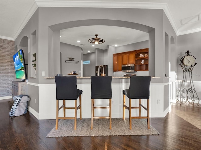 kitchen with ceiling fan, a breakfast bar, ornamental molding, and appliances with stainless steel finishes