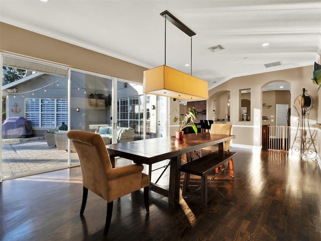 dining space with dark hardwood / wood-style flooring, ornamental molding, and vaulted ceiling