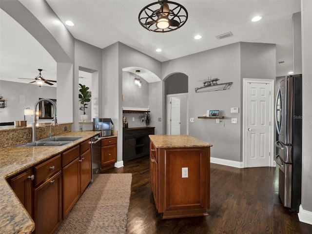 kitchen with light stone countertops, sink, a center island, dark wood-type flooring, and appliances with stainless steel finishes