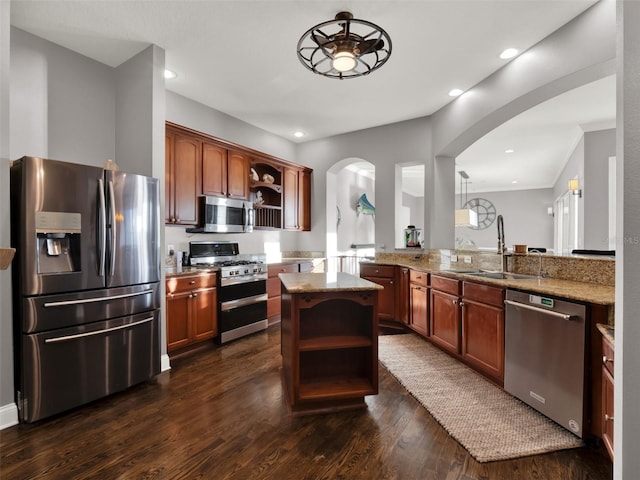 kitchen with sink, dark hardwood / wood-style floors, appliances with stainless steel finishes, light stone counters, and kitchen peninsula