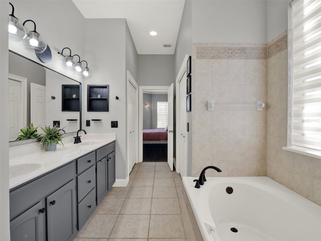 bathroom with tiled tub, tile patterned flooring, and vanity