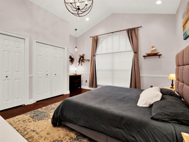 bedroom featuring a chandelier, lofted ceiling, multiple closets, and dark wood-type flooring