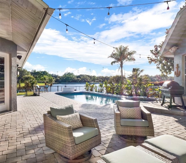 view of swimming pool featuring a water view, grilling area, and a patio area