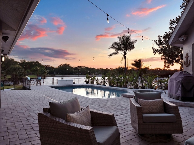 pool at dusk with a patio, a water view, and a grill