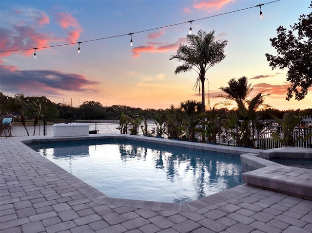 pool at dusk featuring an in ground hot tub