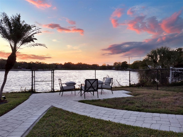 view of dock featuring a yard, a water view, and a patio