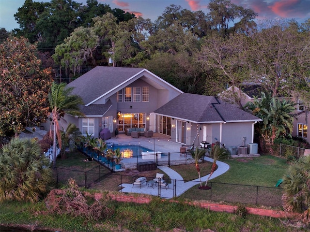 back house at dusk featuring a patio, central air condition unit, outdoor lounge area, a yard, and a fenced in pool