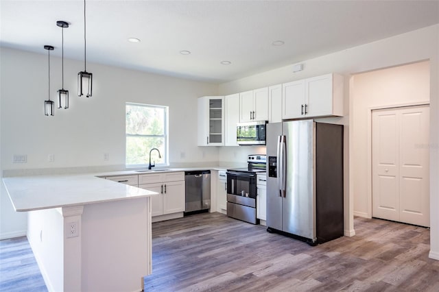 kitchen with appliances with stainless steel finishes, hardwood / wood-style flooring, and kitchen peninsula