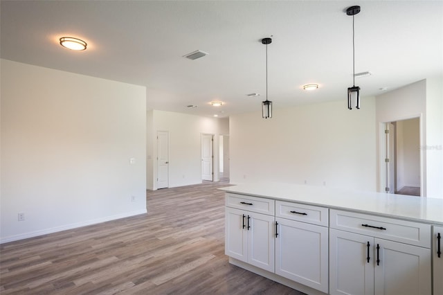 kitchen featuring white cabinets, wood-type flooring, and hanging light fixtures