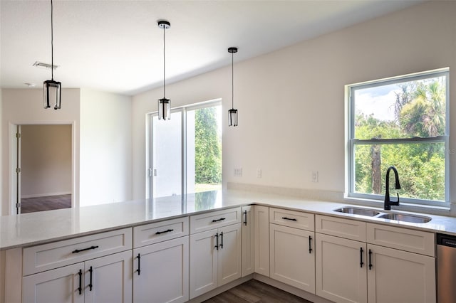 kitchen featuring kitchen peninsula, hanging light fixtures, hardwood / wood-style floors, white cabinets, and sink