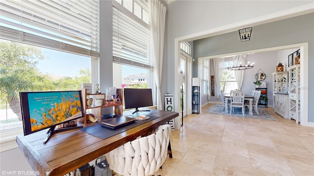 office area featuring plenty of natural light, an inviting chandelier, a high ceiling, and light tile floors