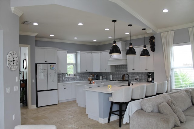 kitchen with white refrigerator, tasteful backsplash, white cabinetry, and a wealth of natural light