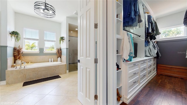 bathroom with plenty of natural light, hardwood / wood-style flooring, and tiled bath