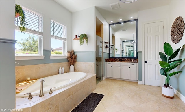 bathroom with vanity, a relaxing tiled bath, and tile flooring