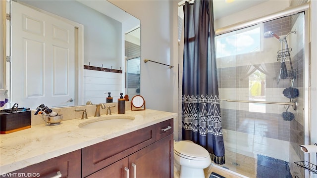 bathroom featuring vanity, toilet, and a shower with shower door