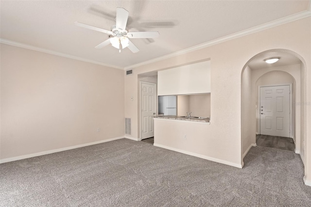 spare room with dark carpet, ceiling fan, and ornamental molding